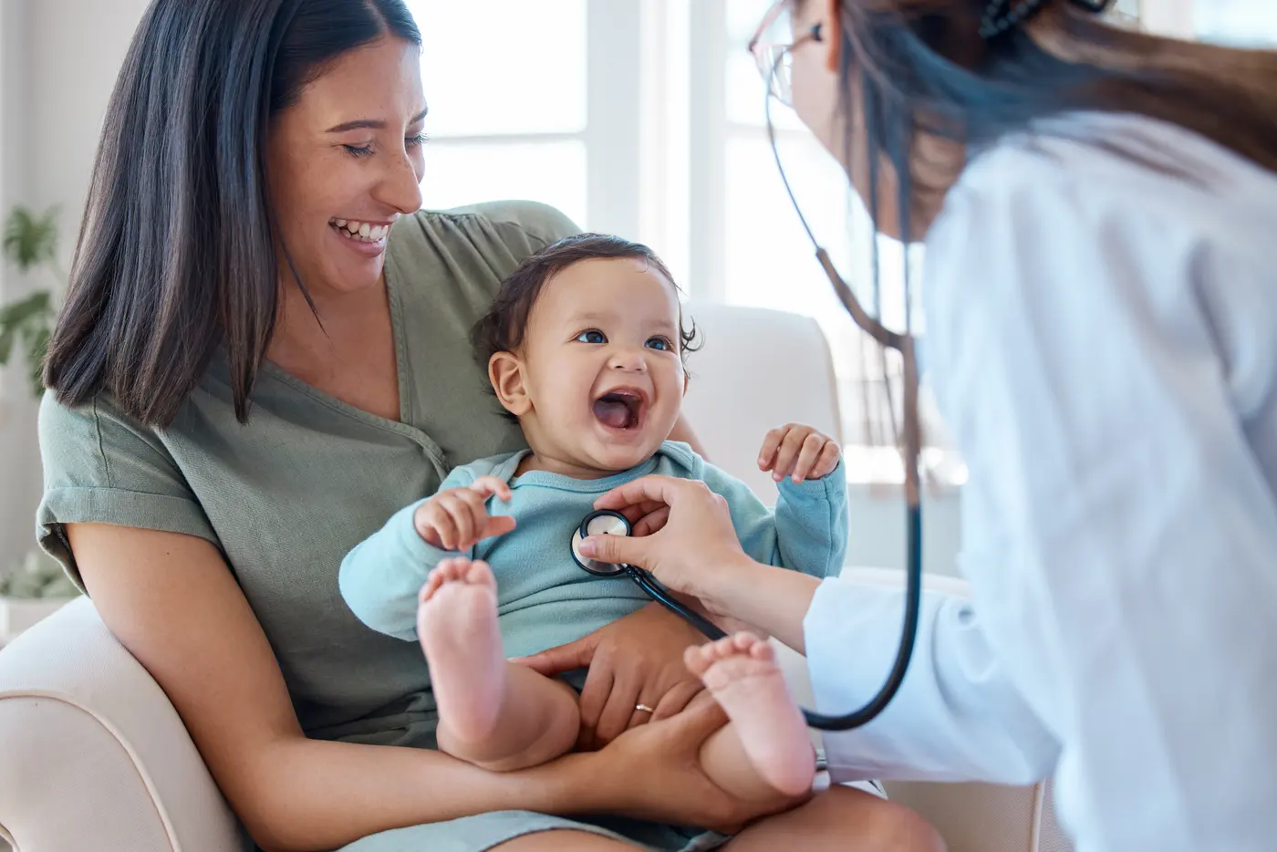 Pediatra revisando a un bebé en brazos de su mamá